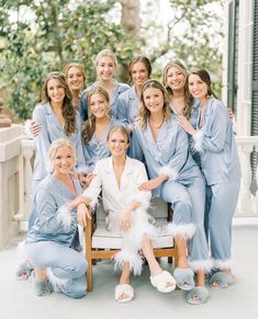 a group of women in blue robes posing for a photo on a porch with their arms around each other