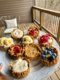 a white plate topped with mini pies covered in toppings and fruit on top of it