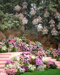 an arrangement of flowers and birdcages hanging from the ceiling in a garden setting