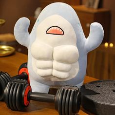 a stuffed animal sitting on top of a wooden table next to two dumbbells