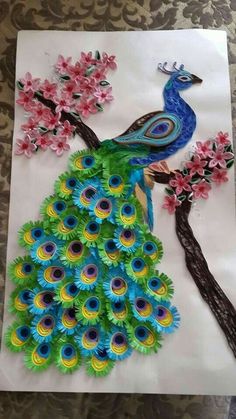 a paper peacock sitting on top of a tree