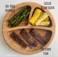 a wooden plate topped with steak and asparagus