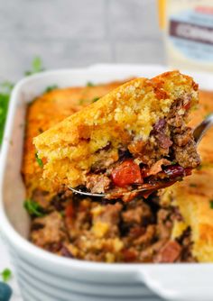 a close up of a spoonful of food in a casserole dish with meat and vegetables