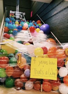 a bunch of balloons that are in some kind of room with a sign on it