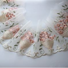 an embroidered necklace with seashells and flowers is shown on a white tablecloth