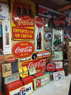 an assortment of coca - cola signs are displayed on the wall