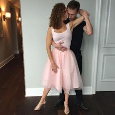 a man and woman standing next to each other in front of a door with their arms around each other