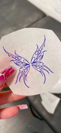 a woman's hand holding a piece of paper with a butterfly drawn on it