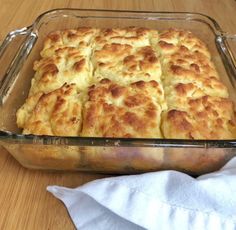 a casserole dish filled with biscuits on top of a wooden table