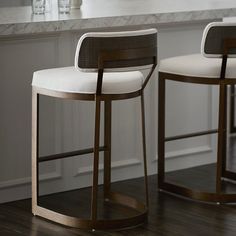 two modern barstools sit in front of a marble countertop