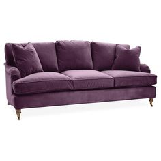 a purple couch with pillows on the back and arms, in front of a white background