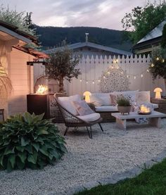 an outdoor patio is lit up with candles and lights on the side of the house