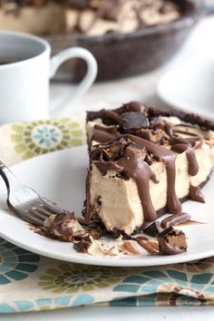 a piece of cheesecake on a plate with a fork and coffee cup in the background