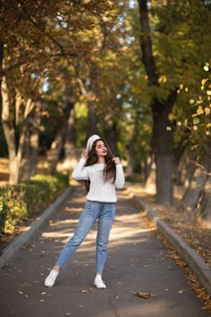 a woman is posing on the side of a tree lined road with her hands behind her head