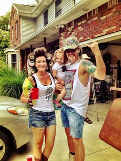 a man, woman and child standing in front of a house