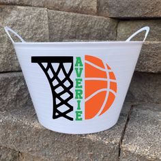 a white bucket with an orange and black basketball on it sitting in front of a stone wall