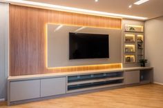 an entertainment center with built - in shelving and lighted shelves, along with a flat screen tv mounted on the wall