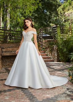 a woman in a white wedding dress standing on a brick walkway