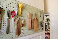 a peg board with various kitchen utensils mounted to it's side wall