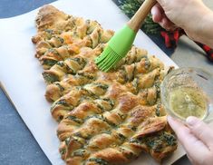 a person holding a green spatula next to a pastry on a cutting board with other food items