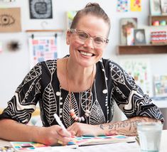 a woman sitting at a table in front of a book and pen with the word c on it