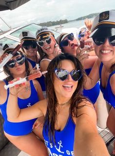 a group of women in blue bathing suits on a boat posing for the camera with their arms around each other