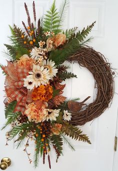 a wreath with flowers and leaves hanging on the front door to welcome someone in their home