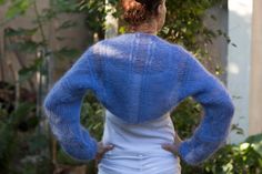 a woman wearing a blue sweater and white skirt standing in front of a house with her back to the camera