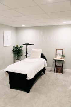 a white and black bedroom with a bed in the corner next to a plant on a table