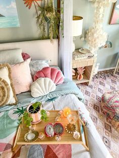 a bed with colorful pillows on top of it next to a tray filled with food