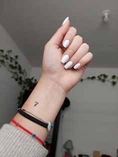 a woman's hand with a white manicure on it and a black band around her wrist