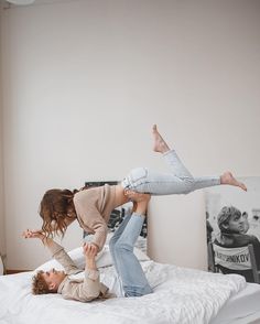 two young women are playing on the bed