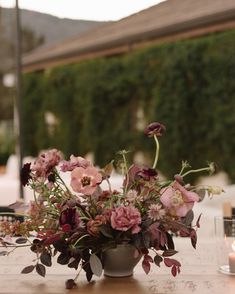 a vase filled with flowers sitting on top of a wooden table next to a candle