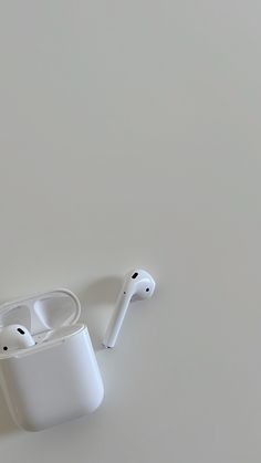 an apple airpods sitting on top of a white table next to another pair of headphones