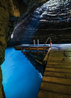 a wooden dock sitting next to a body of water under a cave with blue sky