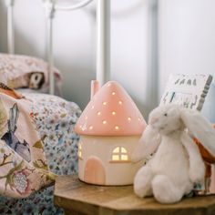 two stuffed animals sitting on a small table next to a bed