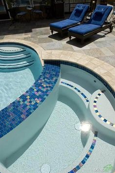 an outdoor swimming pool with blue lounge chairs