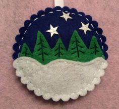 a felt ornament with trees and stars on it