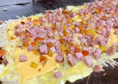 an uncooked pizza with ham and cheese on it