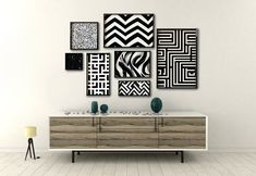 a white wall with black and white art hanging on it's sideboard next to a lamp