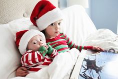 two babies wearing santa hats on top of a bed next to an open laptop computer