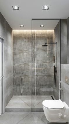 a bathroom with a glass shower door, toilet and stand up shower in the corner