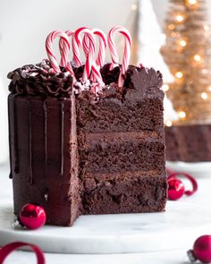 a slice of chocolate cake with candy canes on top and christmas decorations in the background