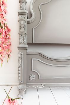 a white bed with pink flowers on the headboard and foot board next to it