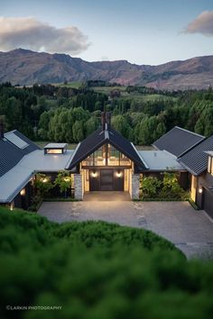 an aerial view of a house with mountains in the background at dusk, taken from above