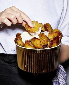 a person in a chef's uniform is holding a bowl with food inside it