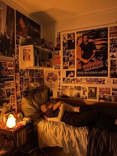 a man laying on top of a bed in a bedroom next to a wall covered with posters