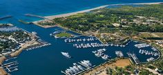 an aerial view of boats docked at a marina in the water near land and trees