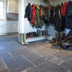 a bunch of boots are hanging on the wall in a room with tile flooring