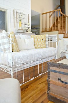 a living room with a white couch and wooden stairs in the background, along with other furniture